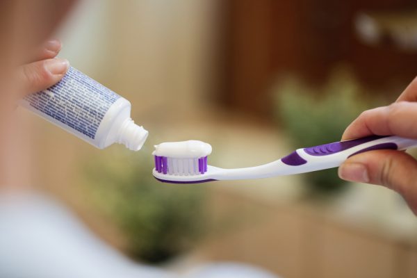 closeup unrecognizable woman applying toothpaste toothbrush bathroom -