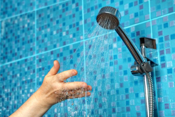 cropped hand woman shower head bathroom -