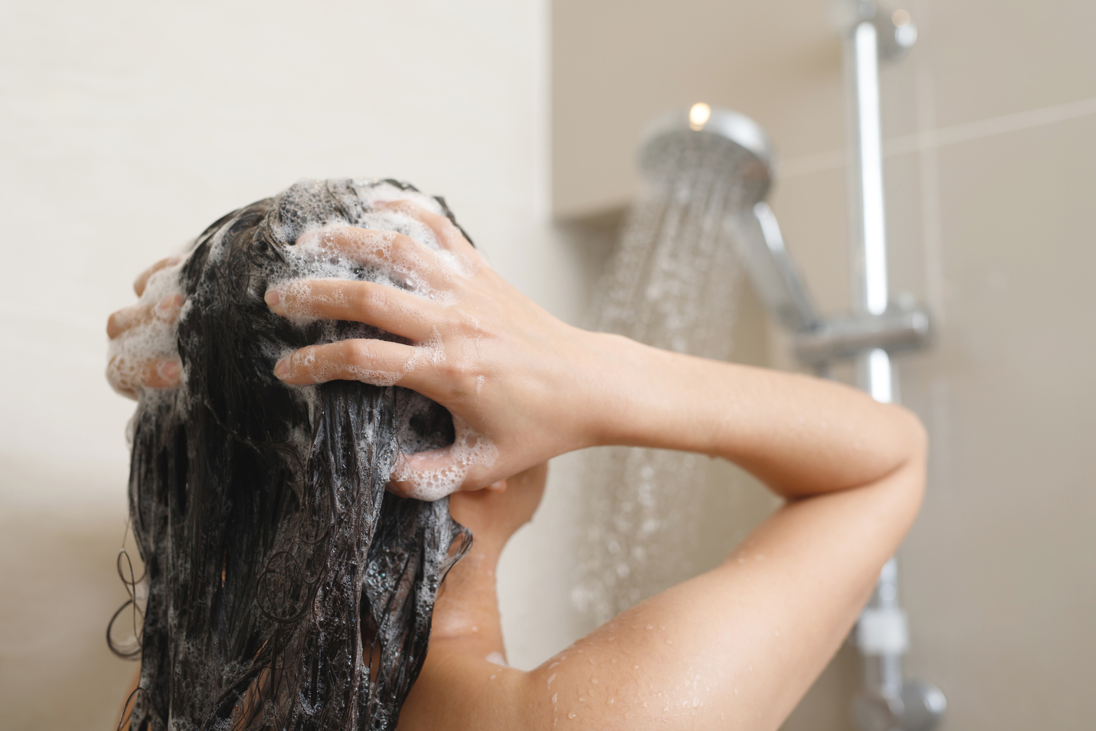 woman taking shower washing hair with shampoo -