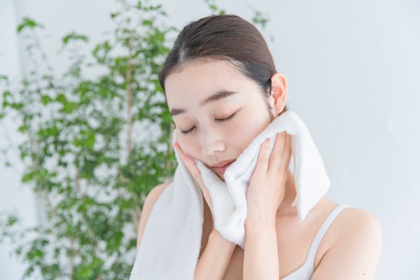 asian japanese young woman dressing face with white bath towel -
