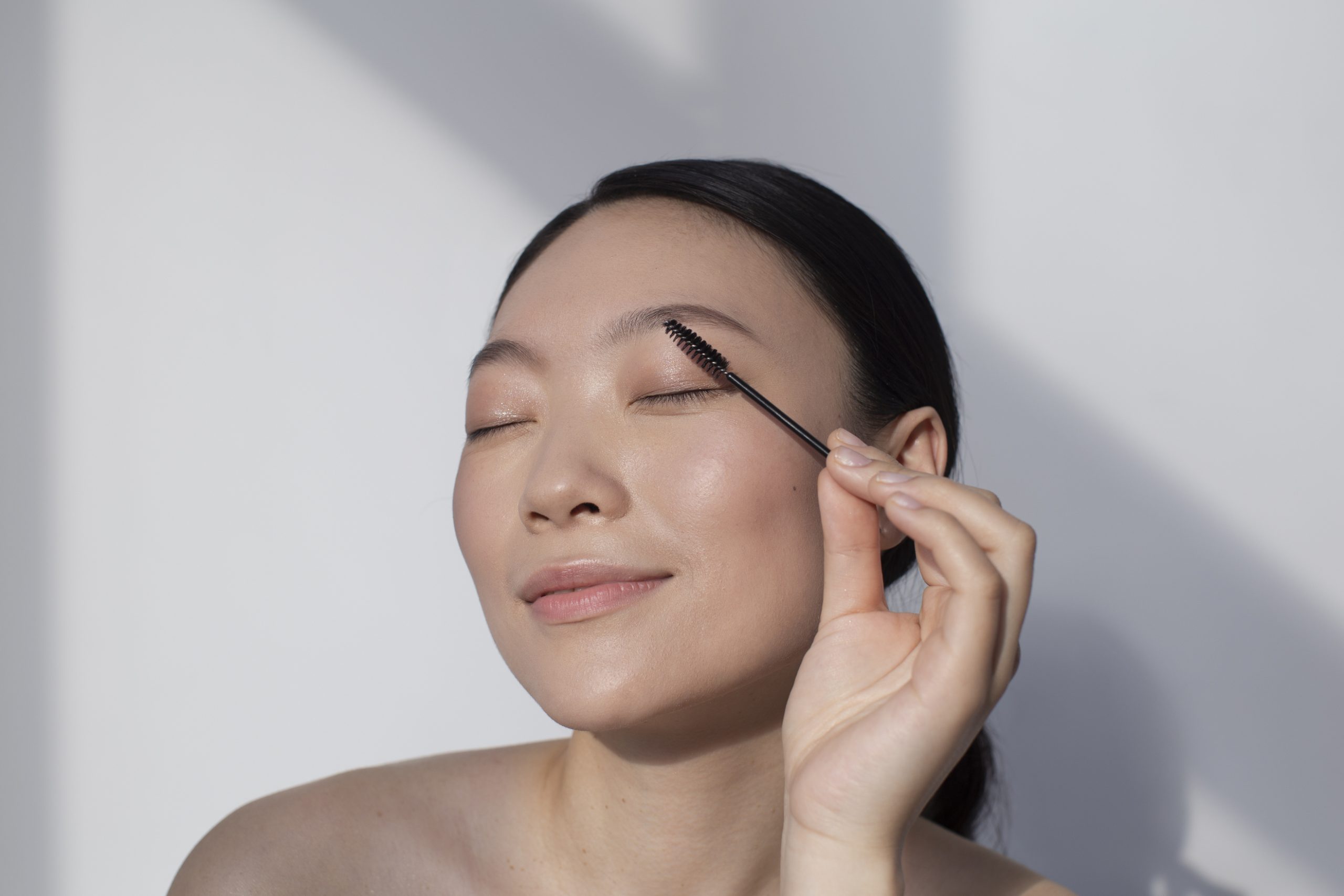asian woman applying mascara scaled -