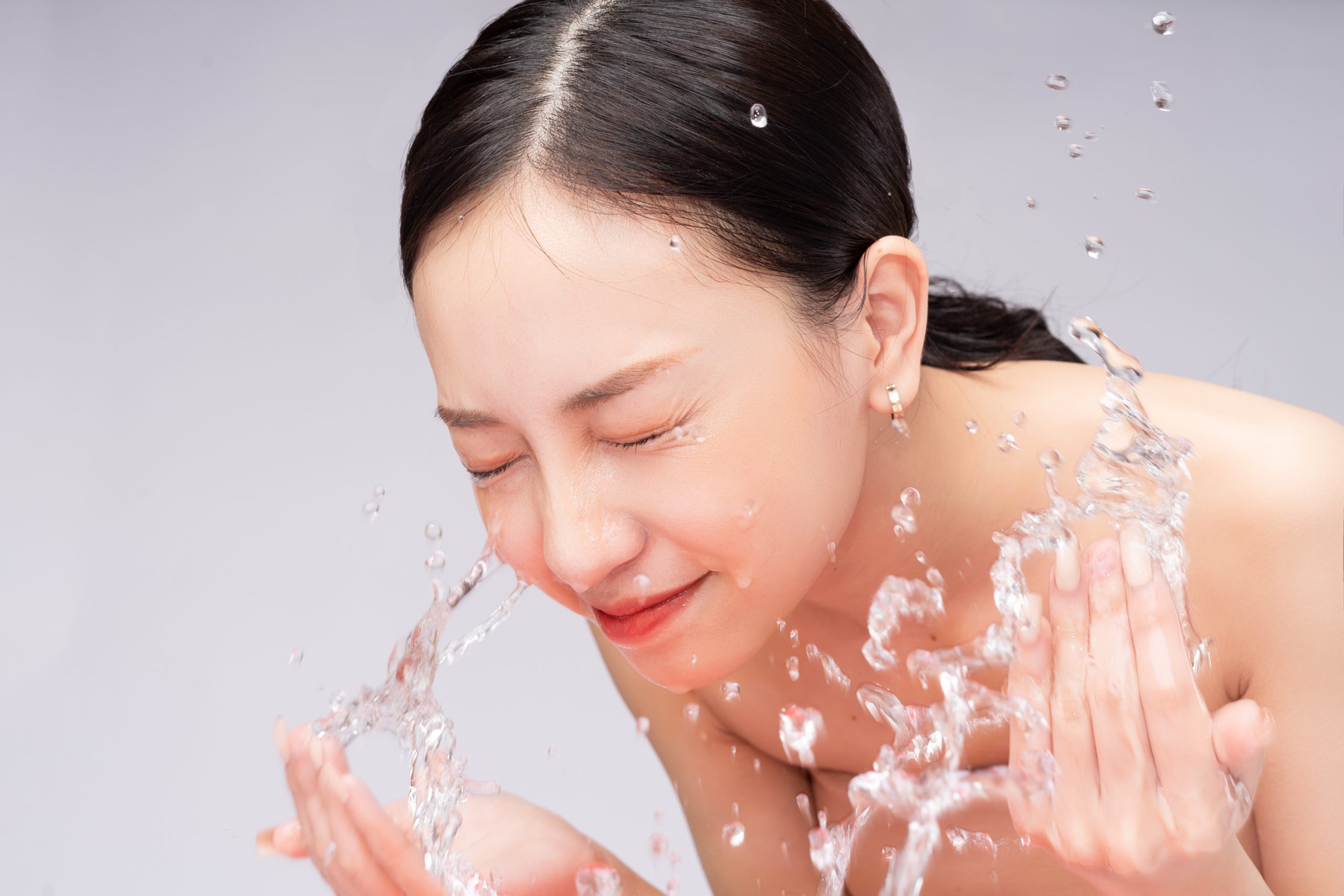beautiful asian woman washes her face with pure water scaled -