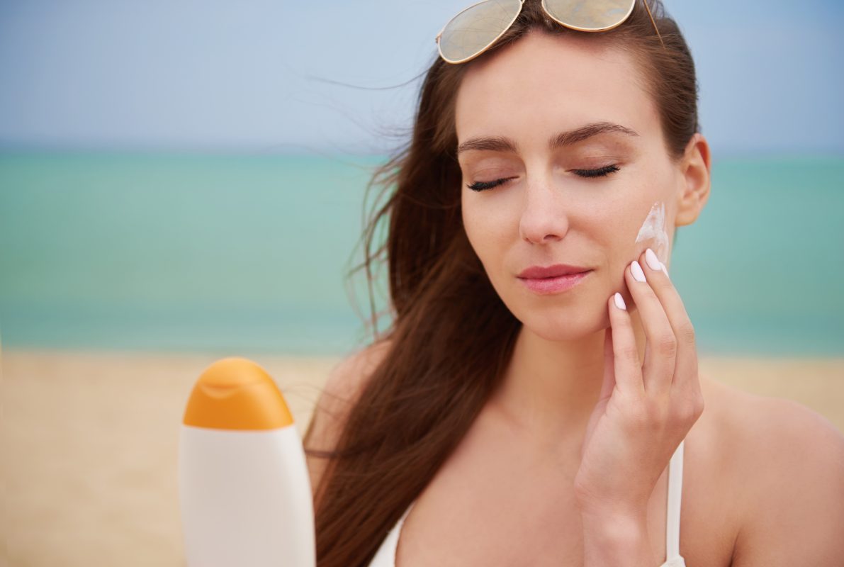 young beautiful woman applying sun cream beach -