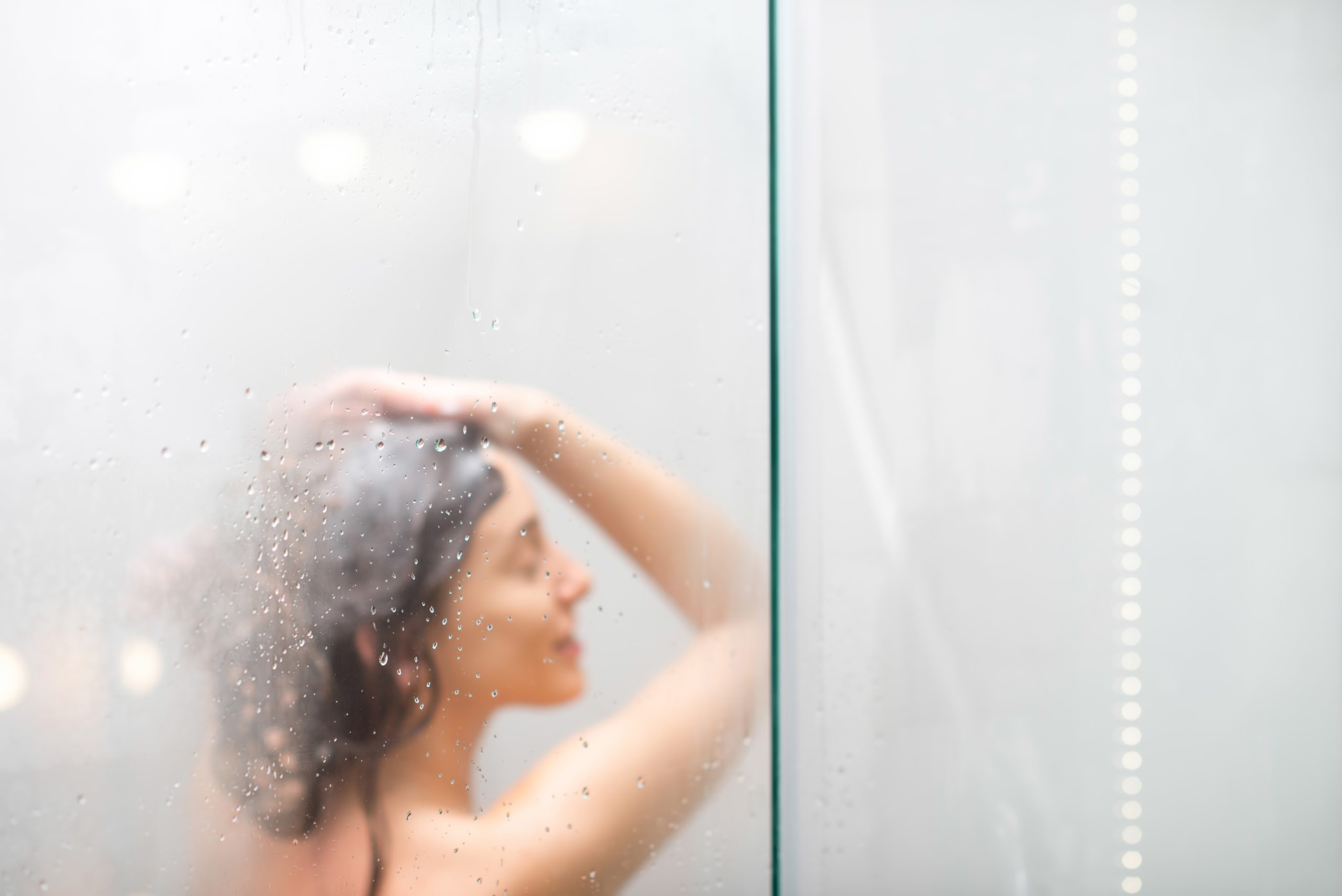 young woman washing hair with shanpoo shower hair care defocused image background scaled -