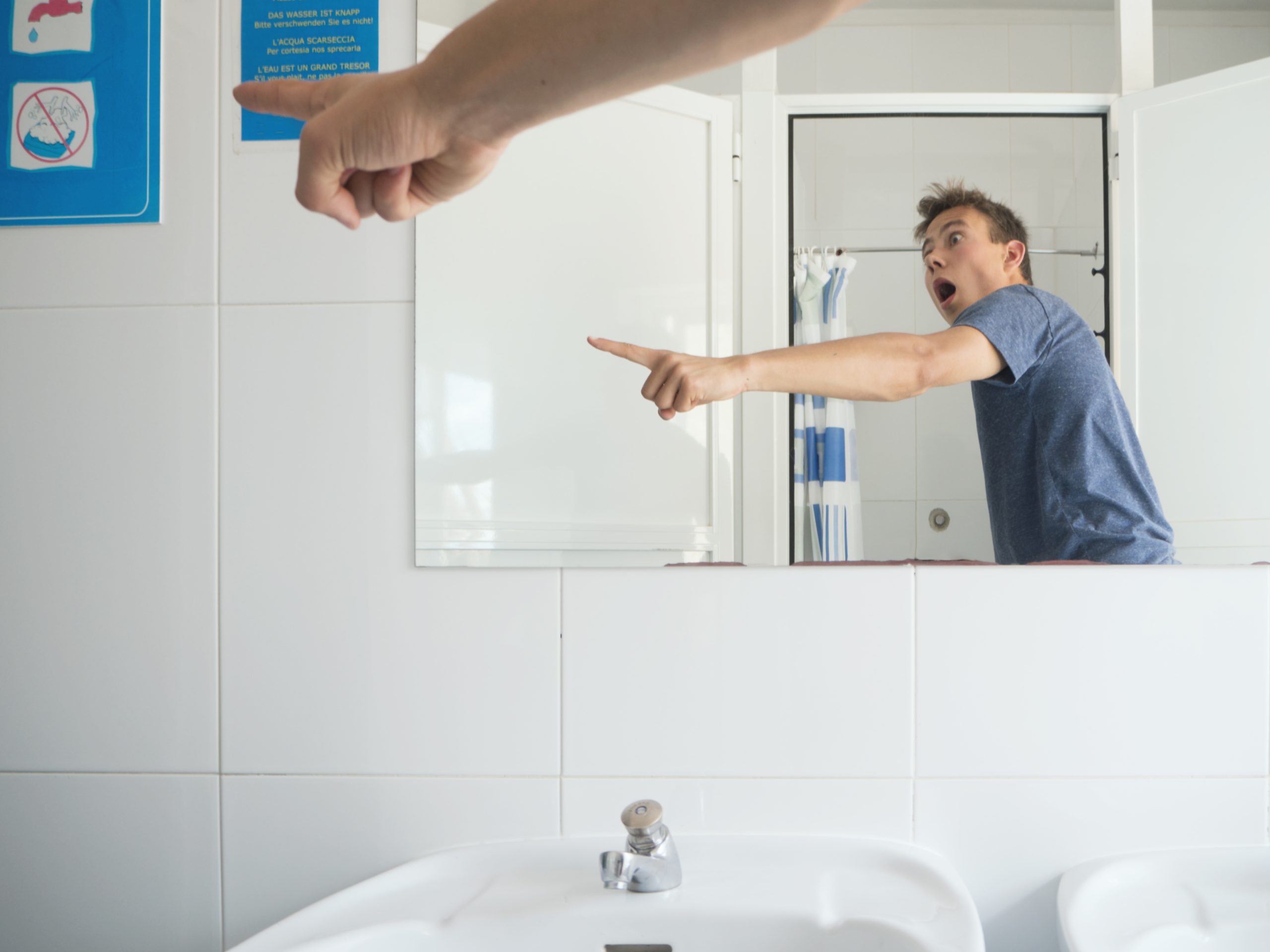 shocked man gesturing sign board while standing bathroom scaled -