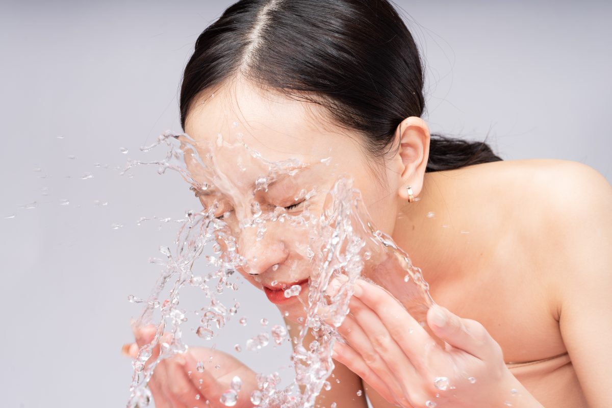 beautiful asian woman washes her face with pure water -