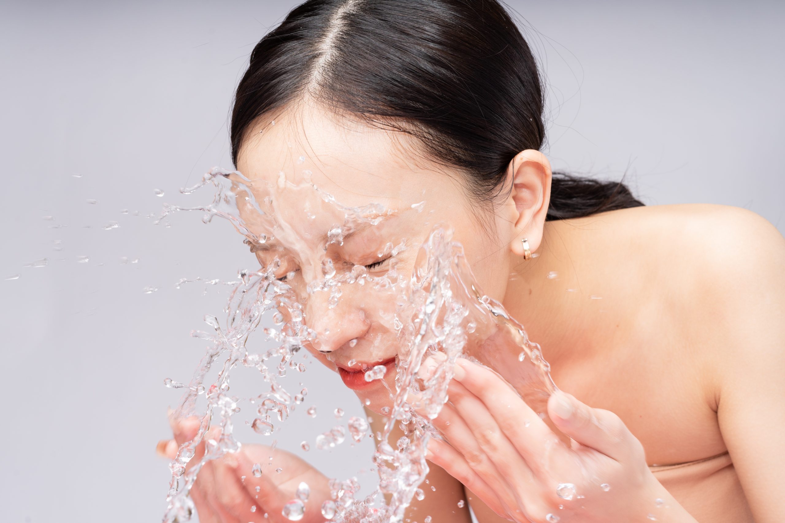 beautiful asian woman washes her face with pure water scaled -